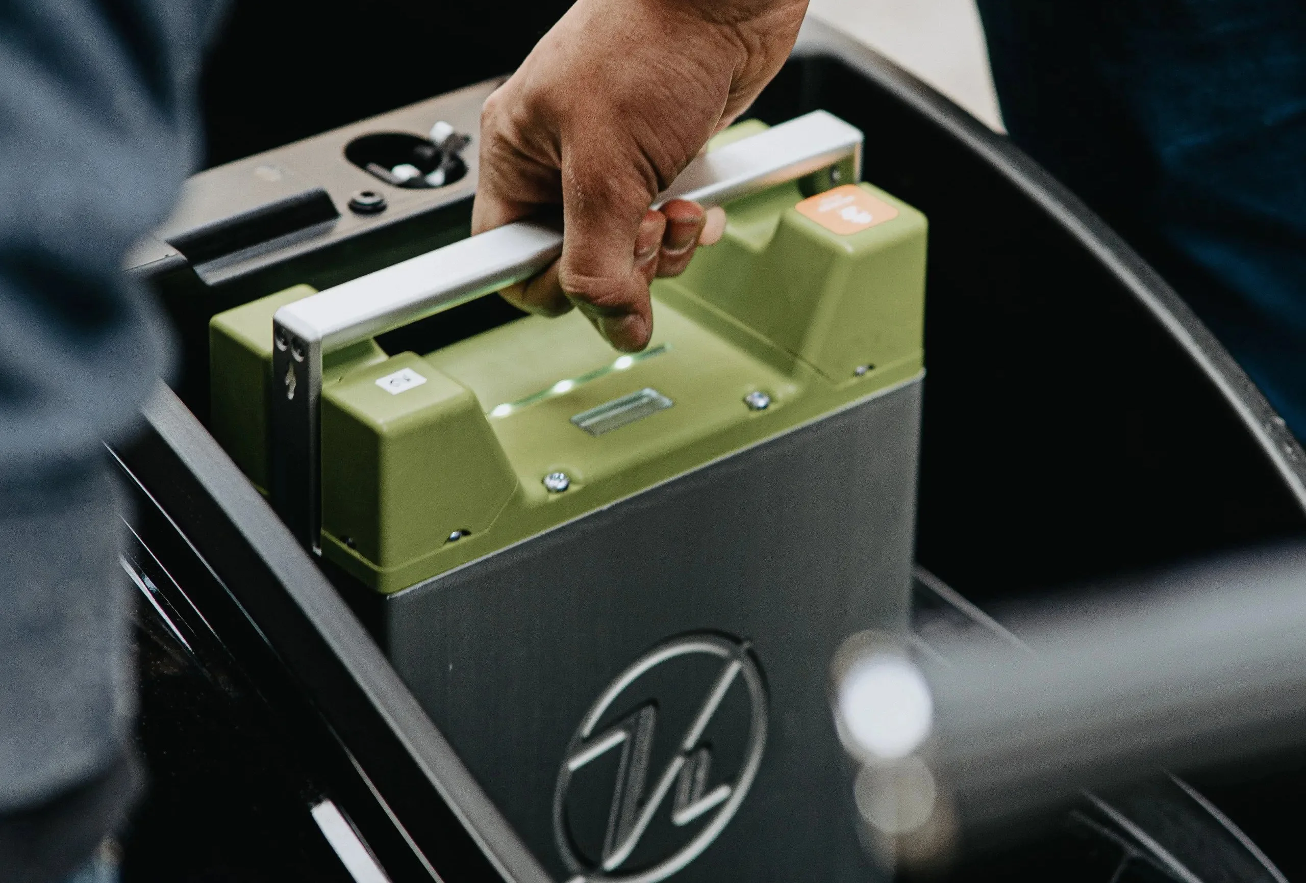 A removable battery being lifted from an electric two-wheeler